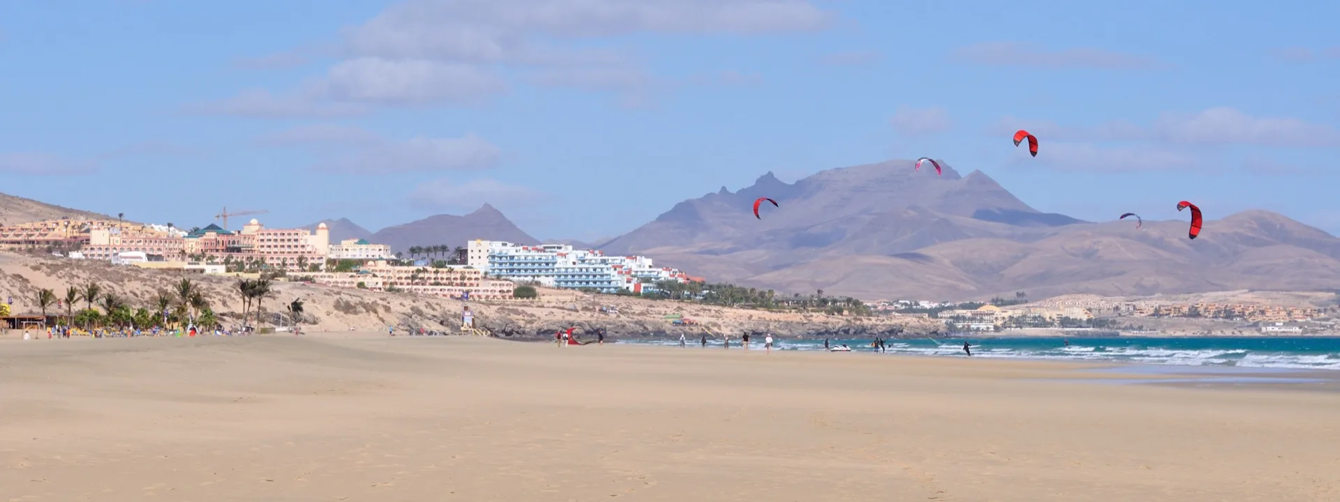Sheltered turquoise bay at Costa Calma backed by hotels and palm trees