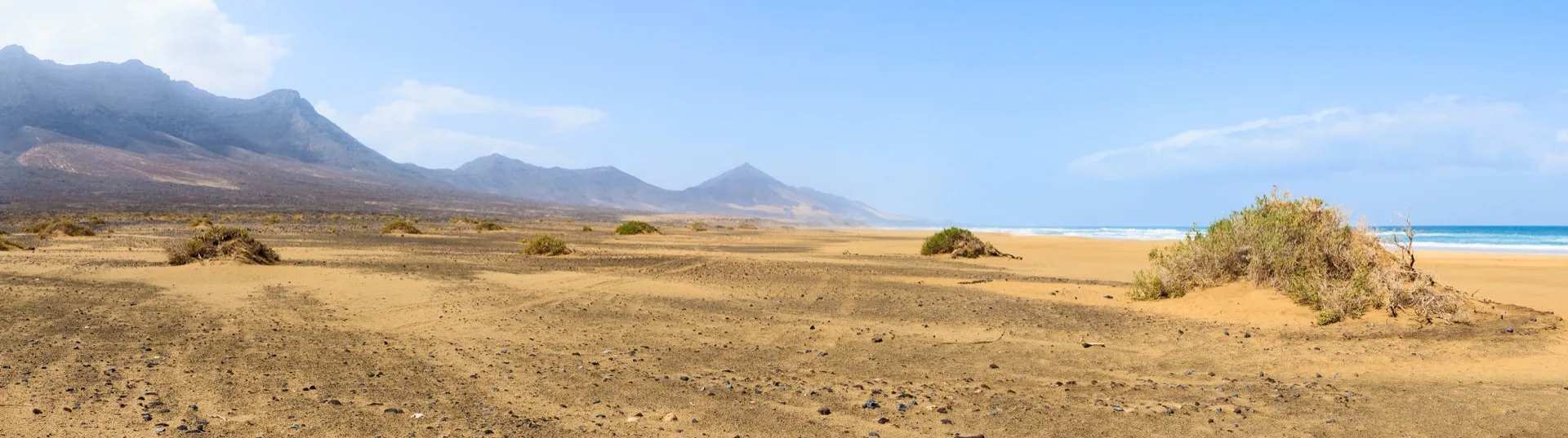 Wide empty wild beach of Cofete on Fuerteventura's Atlantic coast with mountains behind