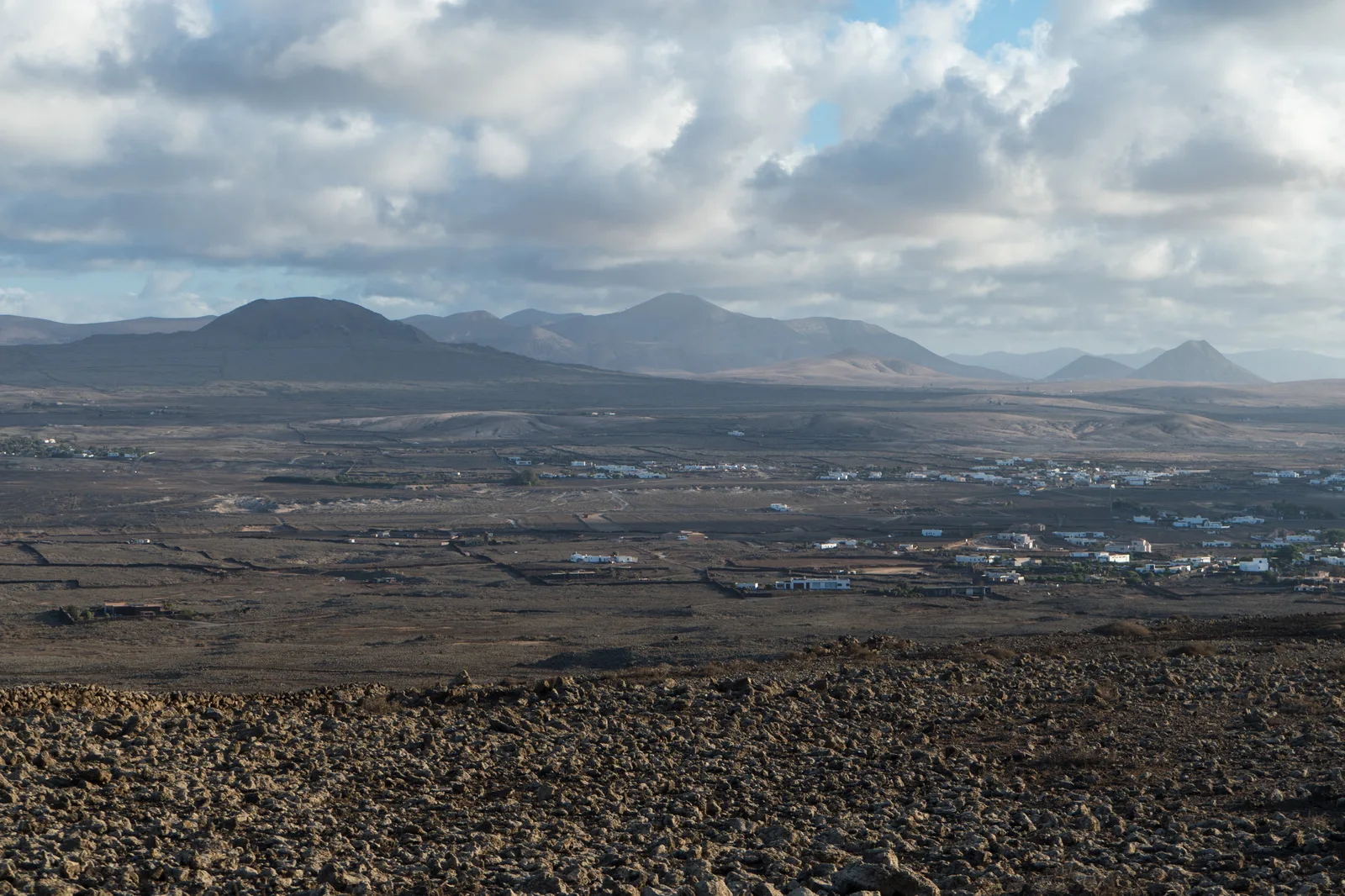 Aerial view of Lajares village scattered across Fuerteventura's volcanic plain, with the cones of Calderón Hondo and Montaña Colorada on the horizon